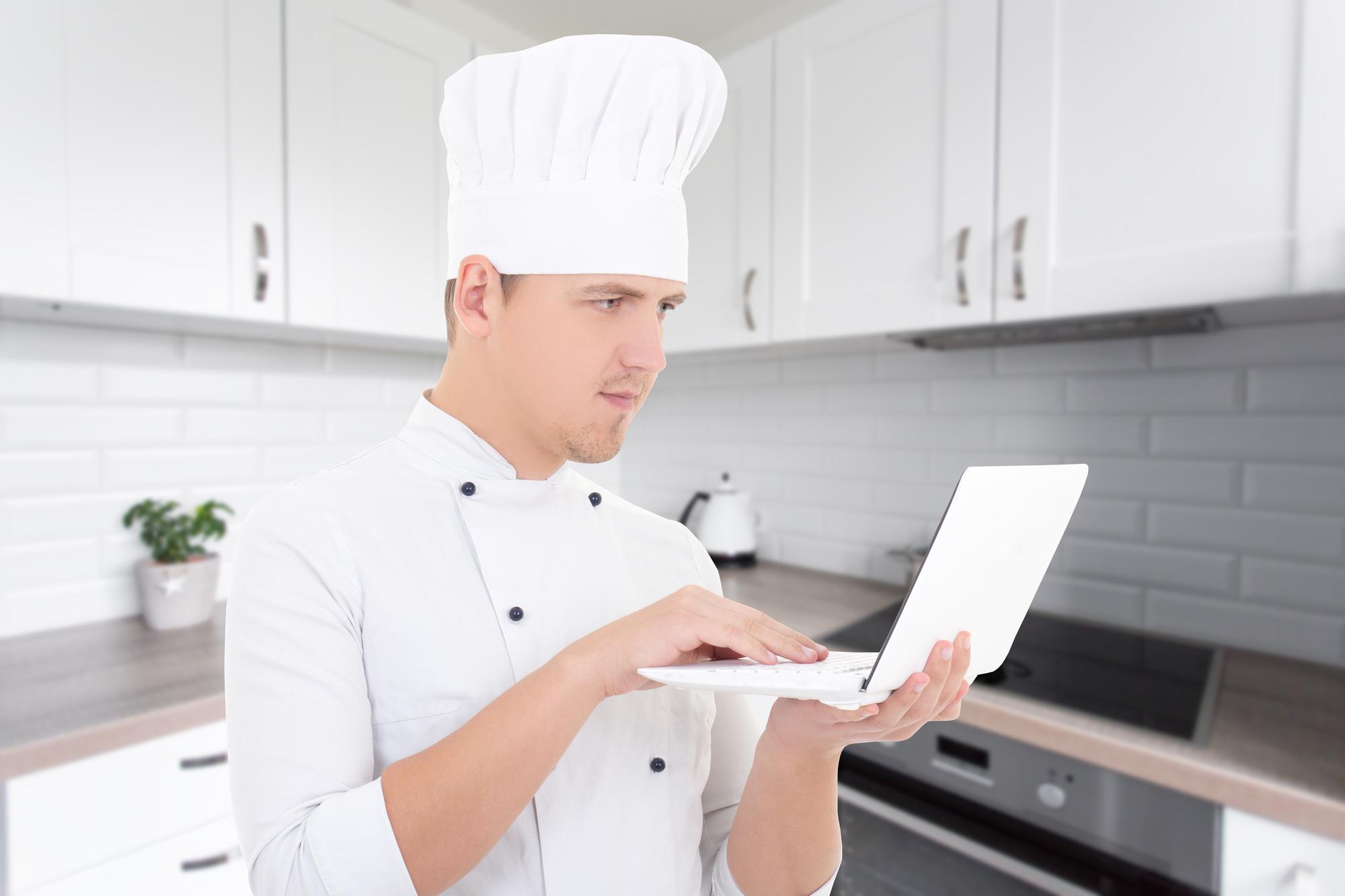 Chef che insegna con telecamera e laptop